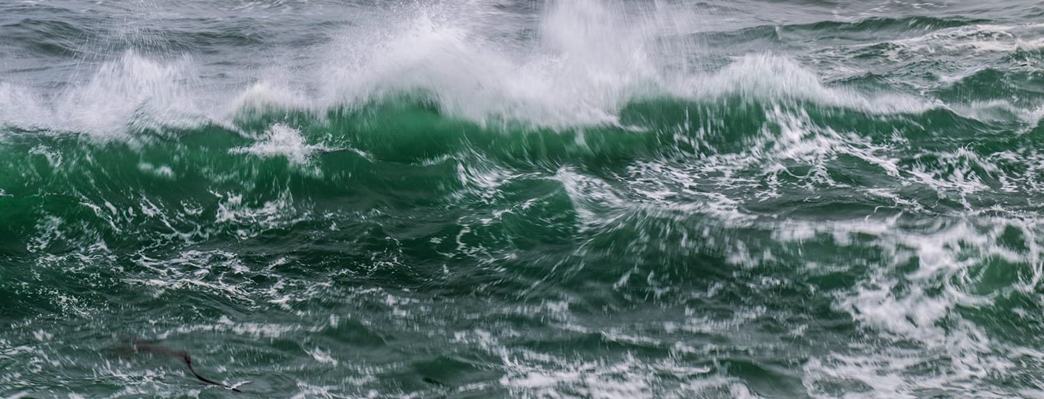 Rank after rank of green ocean swell breaking into white water offshore, Oregon Coast, in heavy weather — the same shape repeating across the whole frame.